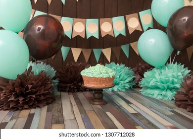  Photo zone with paper garlands, balloons, paper balls, pom poms, confetti and cream cake. Birthday cake. Smash cake. One year. Mint, brown, beige colors. 