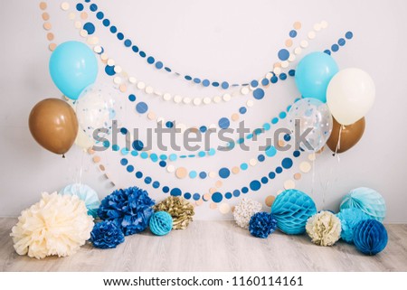 Photo zone with paper garlands, balloons, paper honeycombs, paper balls, pom poms and confetti.  Photo zone for birthday party and smash cake.  Blue, brown, gold, beige, turquoise colors. 