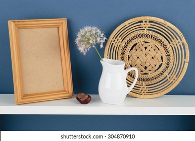 Photoframe And Vase With A Flower On White  Shelf On Blue Wallpaper Background