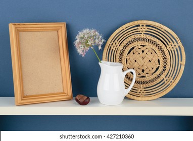 Photoframe And Vase With A Flower On White  Shelf On Blue Wallpaper Background