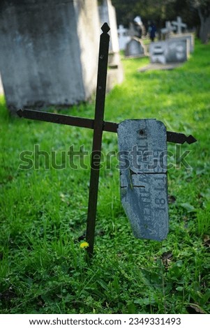 Photograph of an abandoned cemetery. Cross lying on the floor and cross abandoned in time