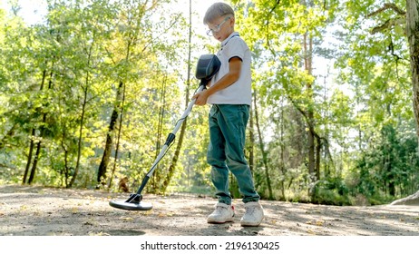 Photograph Of Boy Using A Metal Detector To Search For Lost Treasure On A Sea Sandy Beach