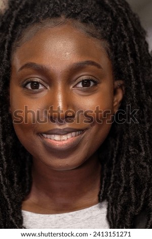 The photograph captures a young Black woman with a soft and confident smile. Her natural twist-out hairstyle perfectly frames her glowing face, highlighting her eyes that sparkle with vivacity. The