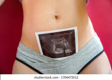 photograph of the embryo, results of perinatal screening in the abdomen of a woman, pregnancy 10 11 12 weeks, on a pink background                               