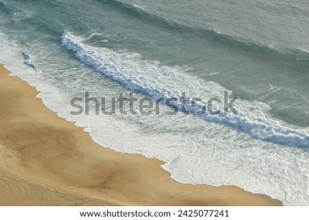 Photograph of the foam of the sea waves on the beach of Nazaré, Portugal