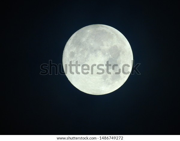 Photograph of full moon with\
clouds