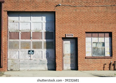 A Photograph Of A Garage Door And Back Door In A City Alley.