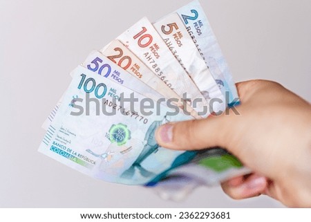 Photograph of Hand holding different Colombian banknotes of different denominations, horizontal image