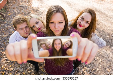 A Photograph Illustrating A Selfie For Social Network With Photobomb Performed By A Young Group Of People.