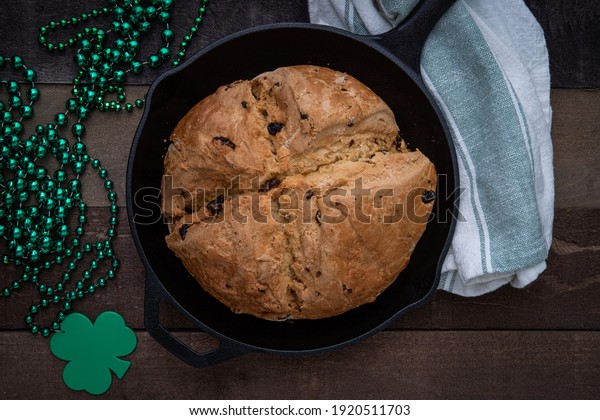 Photograph of Irish\
Soda Bread baked in a cast iron skillet for Saint Patrick\'s Day\
with Shamrock Beads
