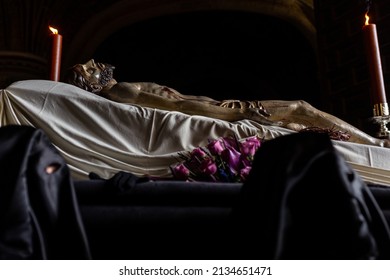 Photograph of jesus lying on his deathbed in a holy week procession in spain. Unrecognizable Nazarenes with a mask on their face carry on their shoulders the body of the dead Christ. - Powered by Shutterstock