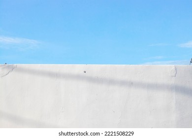 A photograph of the light blue sky above and the white plaster wall below. in the same halving ratio