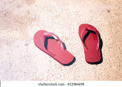 Photograph of a pair of red sandals on a wet floor