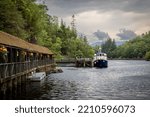 Photograph of a pontoon leading to a small cruise boat on the loch katrine in Scotland on a nice summer afternoon with a beautiful colored sky at the end of the day