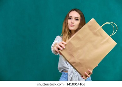 Photograph of a portrait of a beautiful girl woman with long dark flowing hair, loves shopping, on a green background with packages. She is standing in different poses and smiling. Made in studio