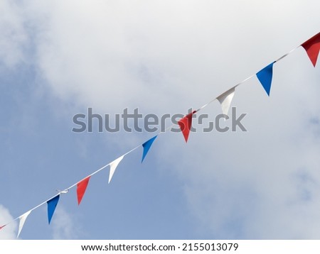Photograph of red white and blue triangular bunting on sky background. Queen Elizabeth's Jubilee 2022.