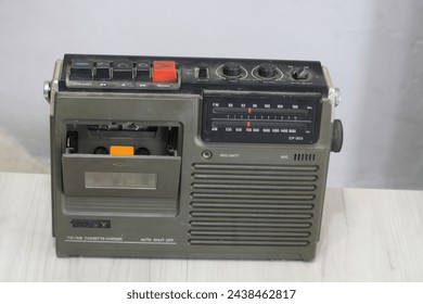 The photograph shows an old Sony brand radio cassette player, model CF-303, on a light wood table. The device has a rectangular design with a dark gray case and a silver stripe on the front.