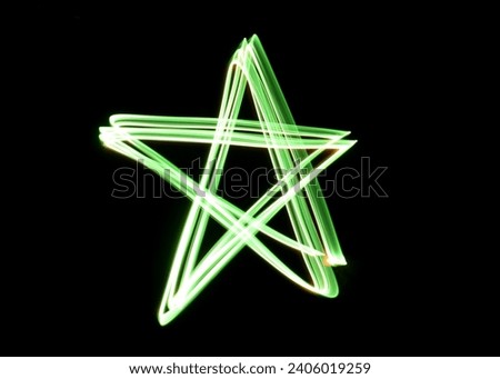 A photograph of a star symbol in vibrant green light in a long exposure photo against a black background. Light painting photography