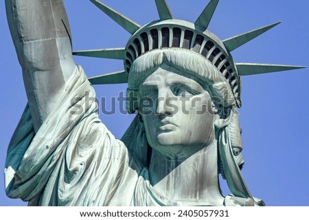 Photograph of the Statue of Liberty holding her torch on a sunny day in Manhattan, known as the lady of New York City and the Big Apple of the USA.