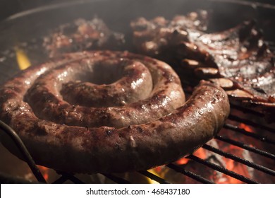 A photograph of Traditional South African Boerewors on a braai. A shallow dept of field with ribs in the background.  - Shutterstock ID 468437180