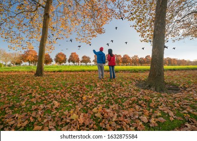 A Photograph Of Two Bird Watching People Surrounded By Autumn Colors