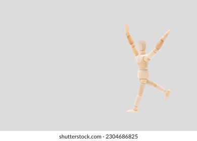 Photograph of a wooden mannequin with light gray background, it is in motion, with arms open and stretched upwards. Photo to be able to cut out. Concepts. Selective focus. Space for copy - Powered by Shutterstock