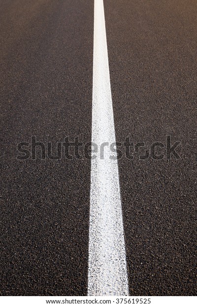   photographed close up of white line road\
markings on the new highway