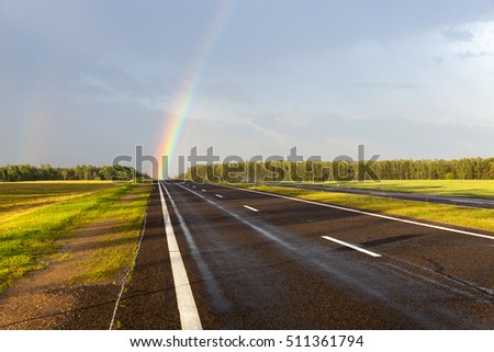   photographed close-up of a rainbow in the rain. Rainbow colored falls directly on the wet highway