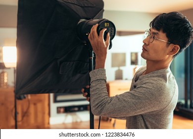 Photographer adjust softbox light intensity in studio. Man setting photographing equipment getting ready for a photo shoot. - Powered by Shutterstock