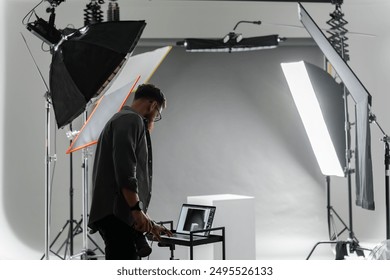 Photographer adjusting camera settings in professional studio with advanced lighting setup - Powered by Shutterstock