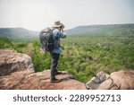 Photographer with backpacks relaxing on top of a mountain and enjoying the view of valley. Young man with camera and backpack enjoying sunset on the peak of mountain .Travel hiking. freedom concept.