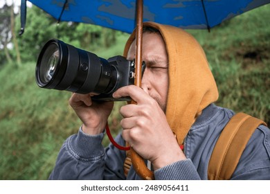 Photographer captures photos under umbrella, protecting camera from rain - Powered by Shutterstock