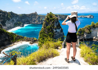 A photographer capturing the scenic view of a blue ocean from a cliffside, surrounded by lush greenery. - Powered by Shutterstock