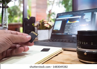 Photographer Concept Memorie Card On Hand Man With Work Space Photographer With DSLR Camera Lense And Computer Laptop