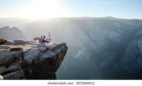 A photographer couple watches the sun set over Yosemite National Park