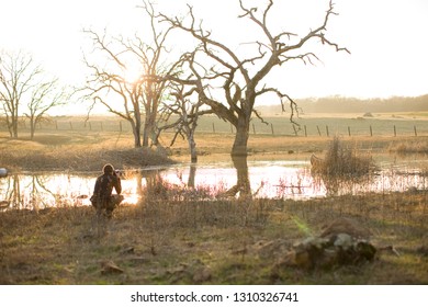 Photographer Crouching Near A Lake.