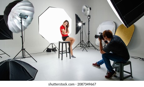 Photographer and cute young teen Asian model working in modern lighting studio with many kinds of flash and accessories. Stock shooting for commercial photo and contents concept. - Powered by Shutterstock