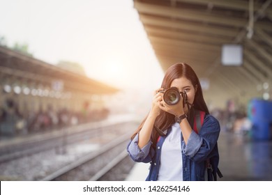 Photographer Girl Smile Holding Digital Camera. Young Asian Woman Traveler With Camera Taking Pictures On Subway Train Platform.  Adventure Hangout Travel Holiday Relaxation Photography Concept.