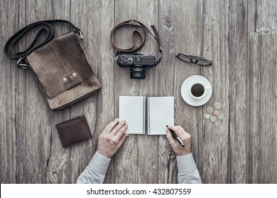 Photographer having a relaxing coffee break, he is writing down notes on a notebook - Powered by Shutterstock