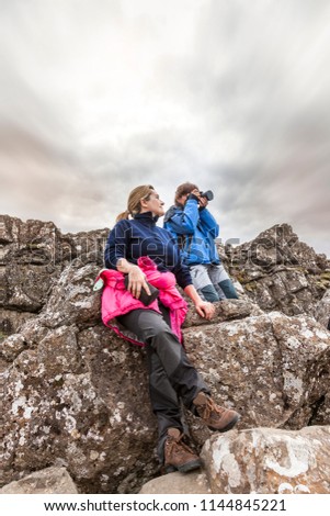 photographer with his assistant takes a picture on the lava rocks in the national park of Pingvellir Iceland