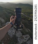 a photographer Holding an APS-C Camera with Telephoto , photograph the nature and green forest during sunset with soft light on trees using landscape photography professional equipments 