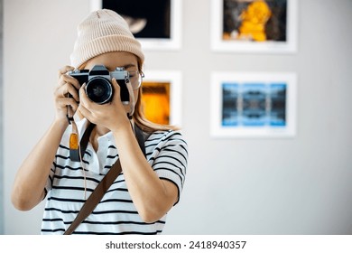 Photographer look viewfinder of her camera at front photo frame show exhibit artwork gallery, Asian woman takes picture art gallery collection in framed paintings pictures on white wall with camera - Powered by Shutterstock