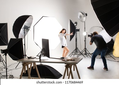 Photographer and model working in modern lighting studio with many kinds of flash and accessories.