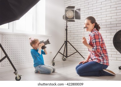 Photographer In Motion. Young Woman Photographer And Child Girl Having Fun At The Photo Session.