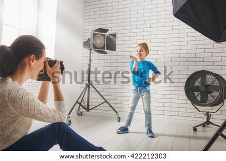 Photographer in motion. Young woman photographs of the child.
