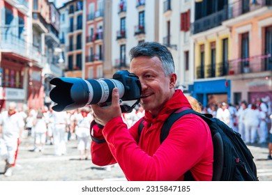 Photographer on San Fermin. Photojournalist. People celebrate San Fermin festival in traditional white and red clothing with red necktie, Pamplona, Navarra, Spain.