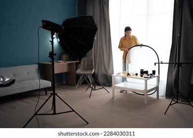 Photographer preparing for shooting by setting up equipment in home photo studio. Copy space