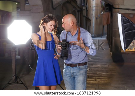 Photographer reviewing photos and talking to model during photo shoot on town street