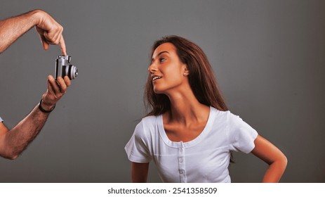 Photographer showing a young woman how to use a vintage camera, teaching her photography skills and sharing knowledge in a studio setting - Powered by Shutterstock