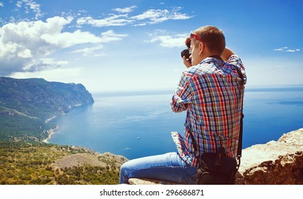 Photographer Sits On Top Of A Mountain And Taking Pictures